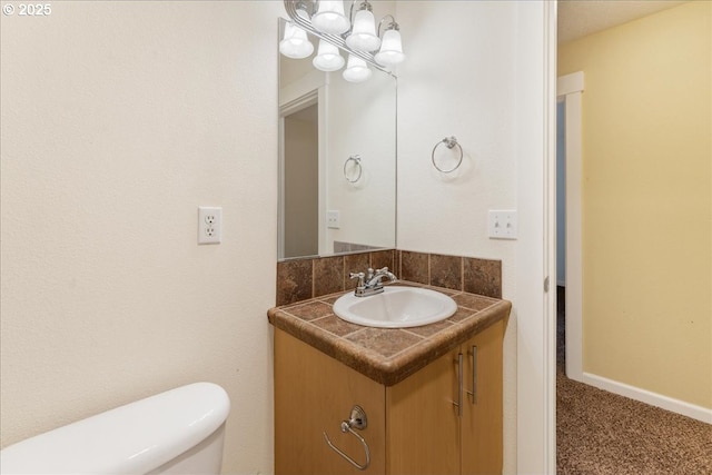 half bathroom featuring toilet, vanity, and baseboards