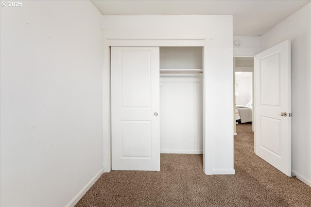 unfurnished bedroom with carpet, a closet, and baseboards