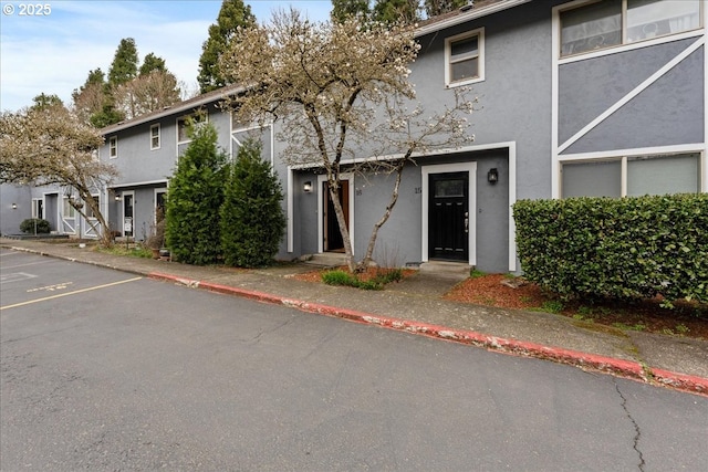 multi unit property with stucco siding and uncovered parking