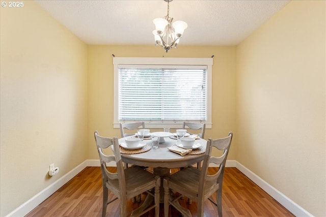 dining room with an inviting chandelier, light wood-style flooring, and baseboards