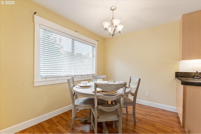 dining space featuring an inviting chandelier, baseboards, and light wood-style floors