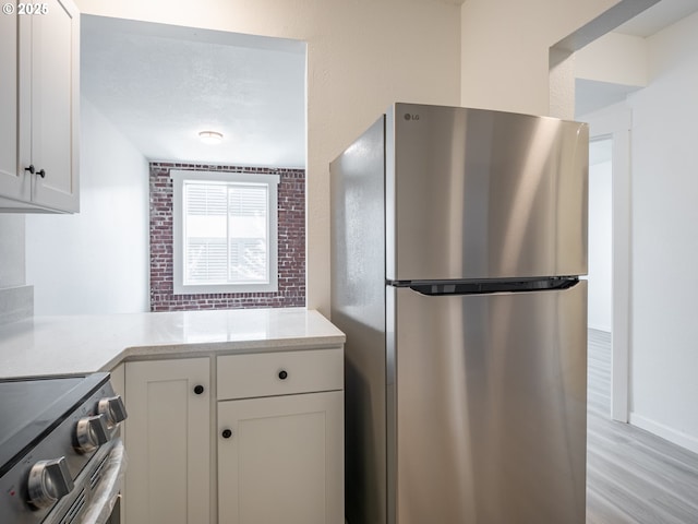 kitchen featuring light wood-style floors, white cabinetry, light stone countertops, and stainless steel appliances