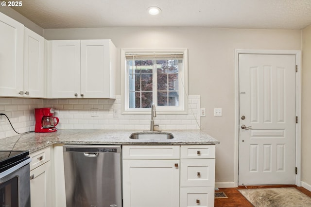 kitchen featuring appliances with stainless steel finishes, a sink, tasteful backsplash, white cabinetry, and baseboards