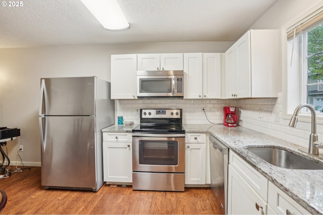 kitchen featuring appliances with stainless steel finishes, a sink, white cabinets, and a textured ceiling