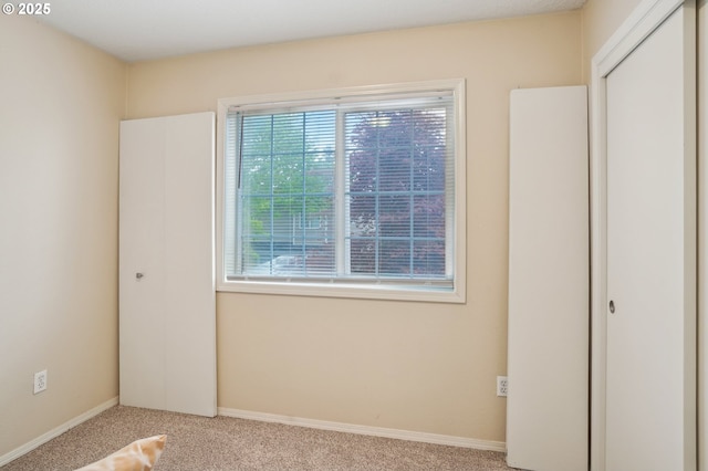 unfurnished room featuring plenty of natural light, carpet, and baseboards