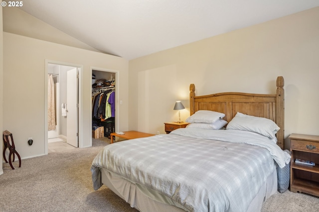 bedroom with carpet flooring, vaulted ceiling, a walk in closet, a closet, and ensuite bathroom