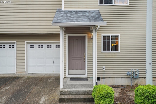 doorway to property featuring asphalt driveway, a garage, and a shingled roof