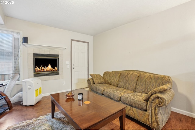living area featuring wood finished floors, baseboards, and a tiled fireplace