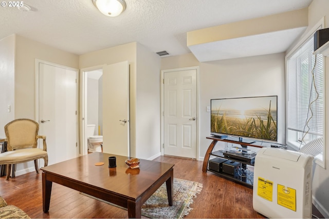 sitting room with wood finished floors, a textured ceiling, and baseboards