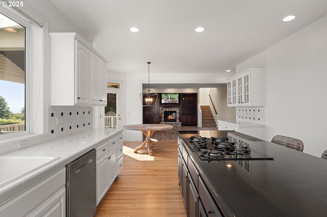 14405 NW Valley View Ln, Portland, OR 97231 - kitchen with dishwasher, a warm lit fireplace, recessed lighting, white cabinets, and black gas cooktop