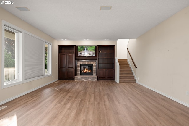 14405 NW Valley View Ln, Portland, OR 97231 - unfurnished living room with light wood-type flooring, stairway, baseboards, and a brick fireplace