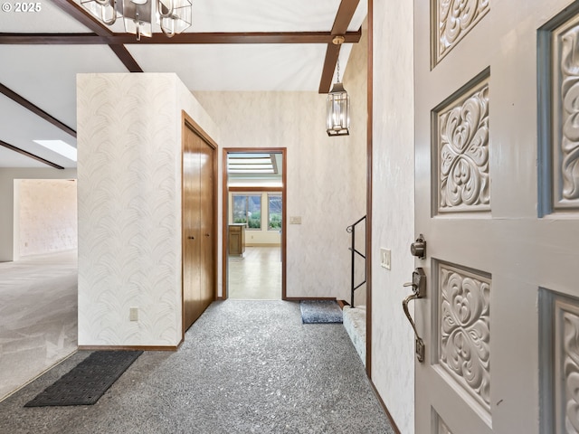 hallway featuring beam ceiling and an inviting chandelier