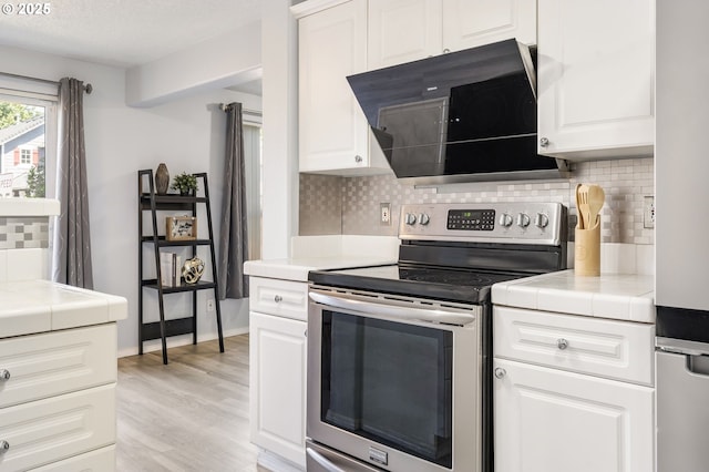 20551 SW Tesoro Ct, Beaverton, OR 97003 - kitchen featuring stainless steel electric range oven, tile countertops, black microwave, tasteful backsplash, and light wood-type flooring