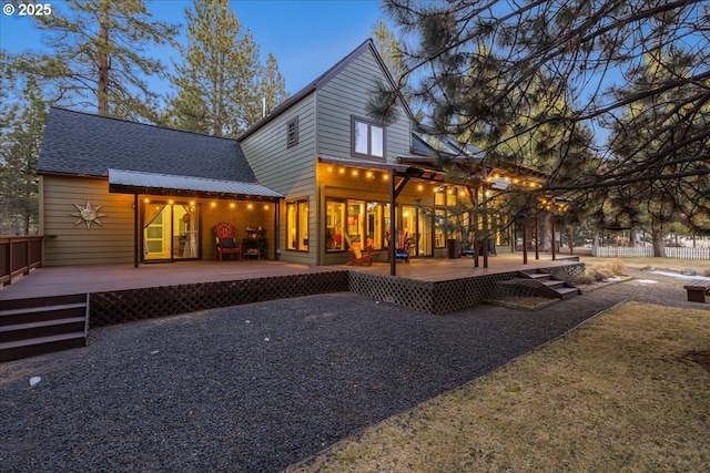 back house at dusk featuring a wooden deck