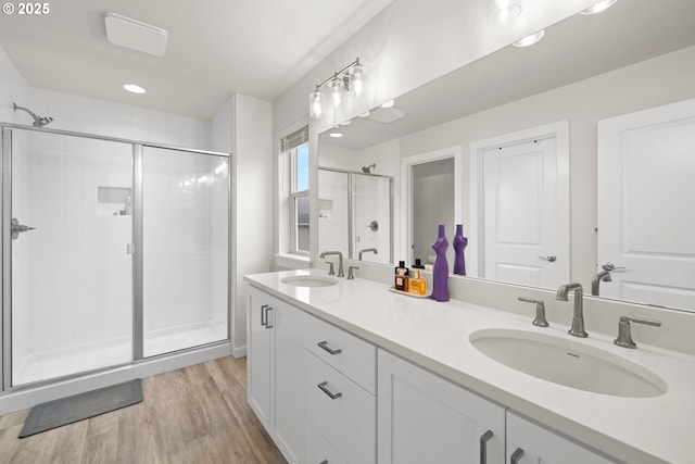 bathroom with a shower with shower door, hardwood / wood-style floors, and vanity