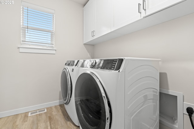 washroom with cabinets, washer and clothes dryer, and light hardwood / wood-style flooring