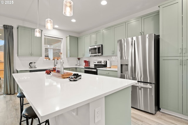 kitchen with a center island, a kitchen bar, decorative backsplash, light wood-type flooring, and appliances with stainless steel finishes