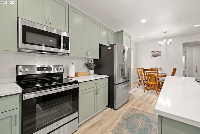 kitchen featuring tasteful backsplash, a notable chandelier, light hardwood / wood-style floors, green cabinetry, and stainless steel appliances