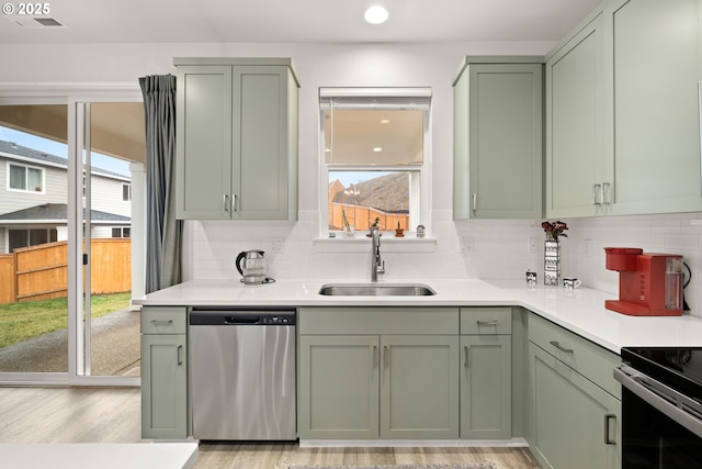 kitchen with stainless steel dishwasher, backsplash, sink, and green cabinetry