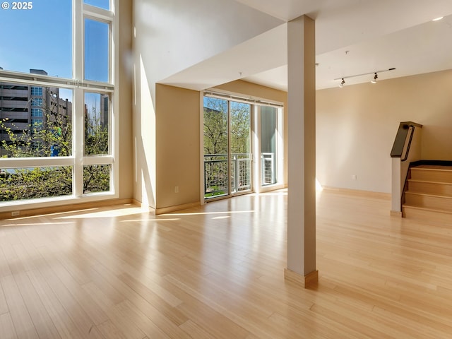 12600 SW Crescent St Unit 219, Beaverton, OR 97005 - unfurnished living room featuring stairway, rail lighting, baseboards, and wood finished floors