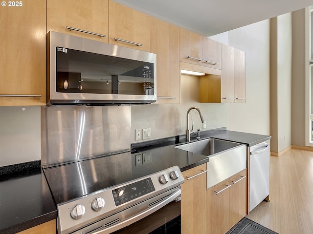 12600 SW Crescent St Unit 219, Beaverton, OR 97005 - kitchen featuring stainless steel appliances, dark countertops, light brown cabinets, a sink, and baseboards