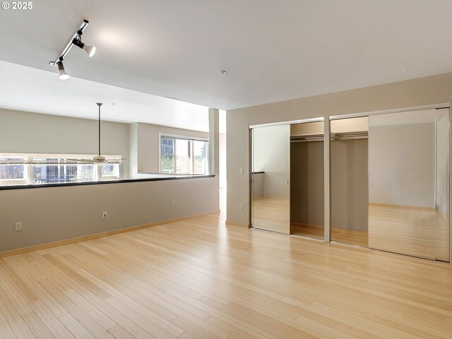 12600 SW Crescent St Unit 219, Beaverton, OR 97005 - unfurnished bedroom with track lighting, light wood-style flooring, multiple closets, and baseboards