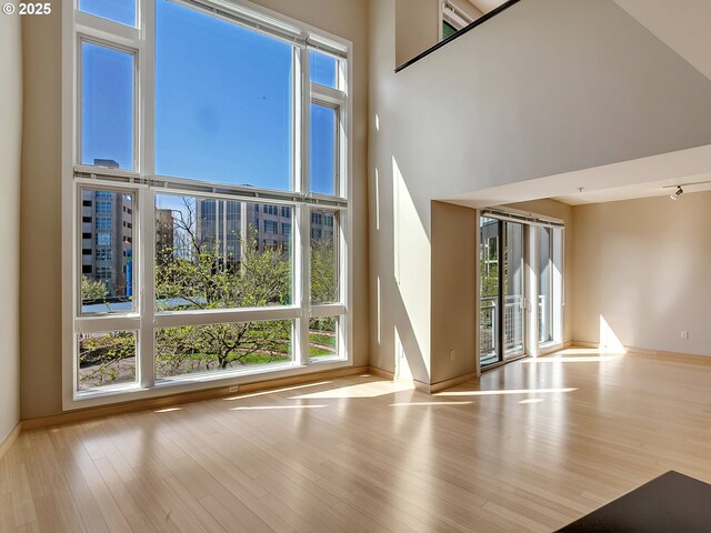 12600 SW Crescent St Unit 219, Beaverton, OR 97005 - unfurnished living room featuring baseboards, a healthy amount of sunlight, and a towering ceiling