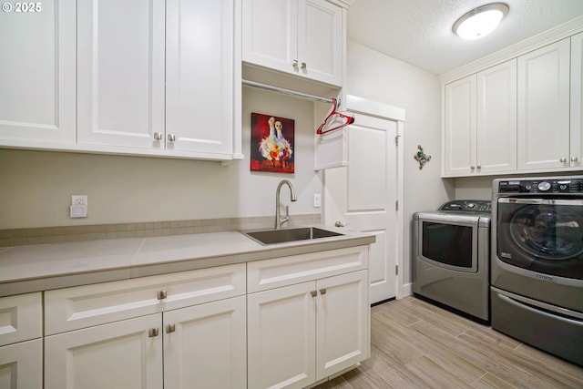 1715 York Butte Ave, Salem, OR 97306 - laundry room featuring a sink, cabinet space, a textured ceiling, washer and clothes dryer, and light wood-type flooring