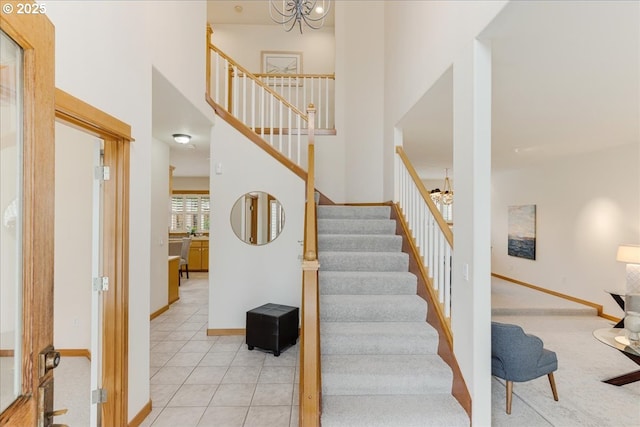 staircase featuring baseboards, a chandelier, a towering ceiling, and tile patterned flooring