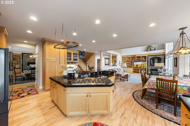 kitchen with built in shelves, stainless steel appliances, light brown cabinets, a center island, and light hardwood / wood-style floors