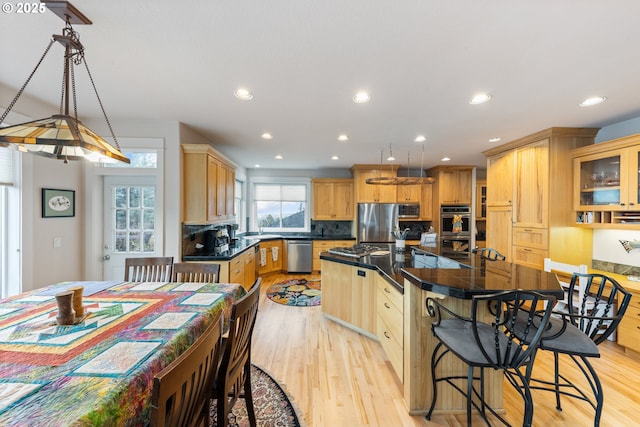 kitchen featuring pendant lighting, light brown cabinets, stainless steel appliances, and a center island