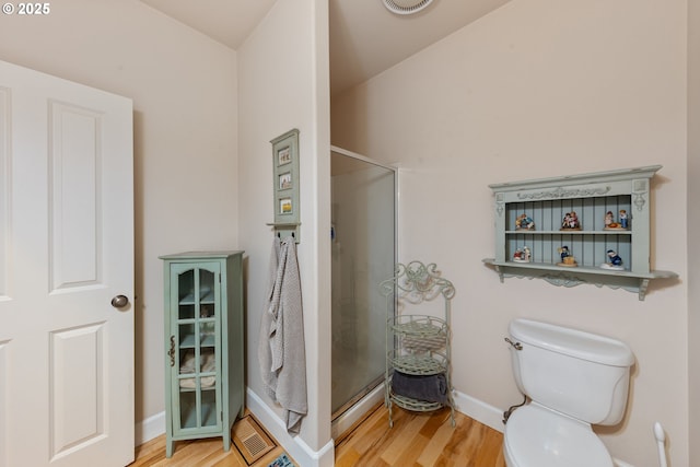 bathroom featuring hardwood / wood-style flooring, toilet, and a shower with shower door