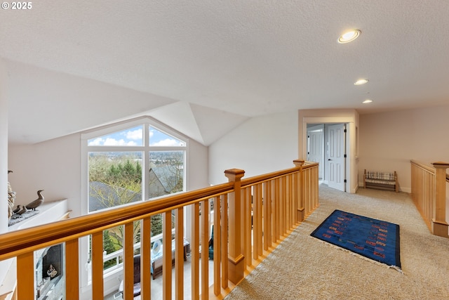 hall with a textured ceiling, light carpet, and lofted ceiling