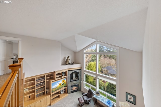 interior space featuring a textured ceiling, carpet floors, a fireplace, and vaulted ceiling