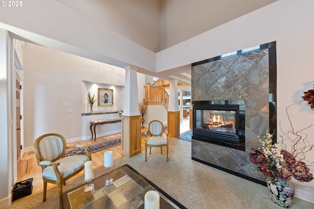 living room featuring a fireplace, a high ceiling, and decorative columns