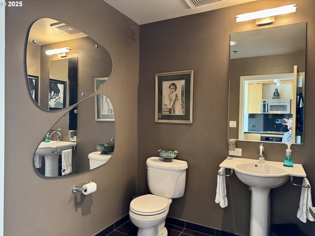 half bath with visible vents, toilet, and tile patterned floors