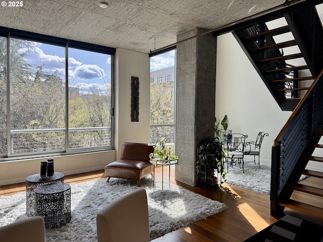 sitting room with stairs, plenty of natural light, baseboards, and wood finished floors