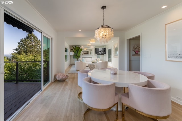 dining room with ornamental molding, a notable chandelier, and light hardwood / wood-style flooring