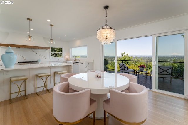 dining area featuring light wood-type flooring, a notable chandelier, and crown molding