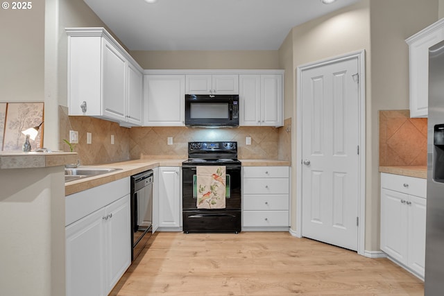 kitchen featuring decorative backsplash, light wood-style floors, light countertops, white cabinets, and black appliances
