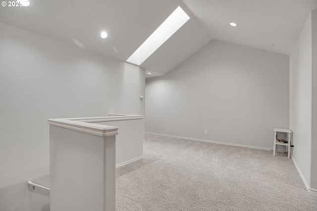 carpeted empty room with recessed lighting, baseboards, and vaulted ceiling with skylight