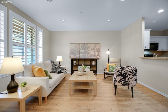 living area featuring recessed lighting, baseboards, and light wood-style flooring