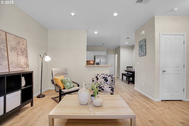 living area with recessed lighting, baseboards, and light wood-type flooring