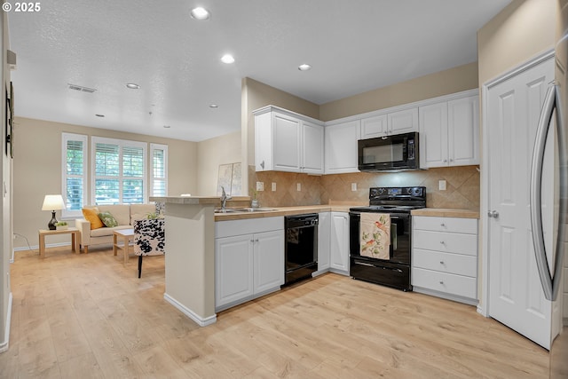 kitchen with white cabinets, recessed lighting, light wood finished floors, and black appliances