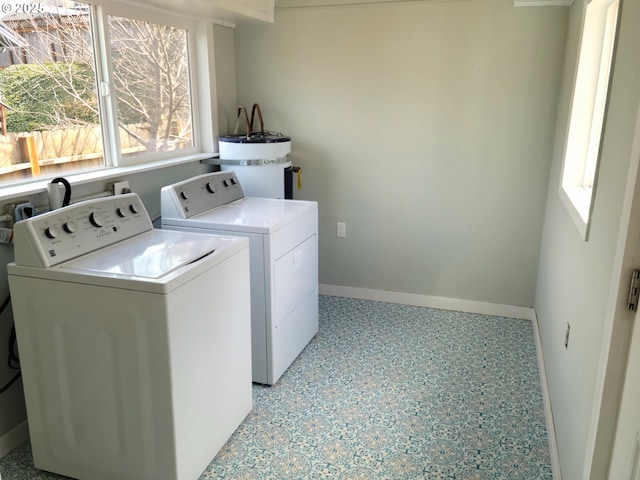 washroom featuring washing machine and clothes dryer, laundry area, baseboards, and water heater