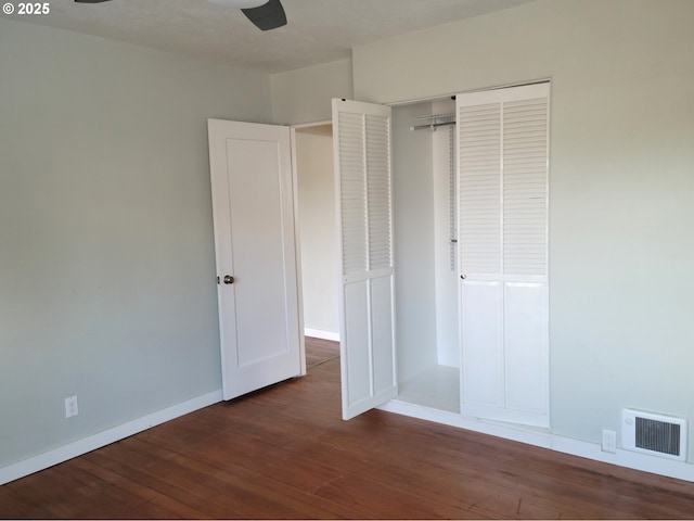 unfurnished bedroom with visible vents, dark wood-style flooring, and baseboards