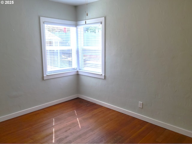 spare room with baseboards, a healthy amount of sunlight, and hardwood / wood-style floors