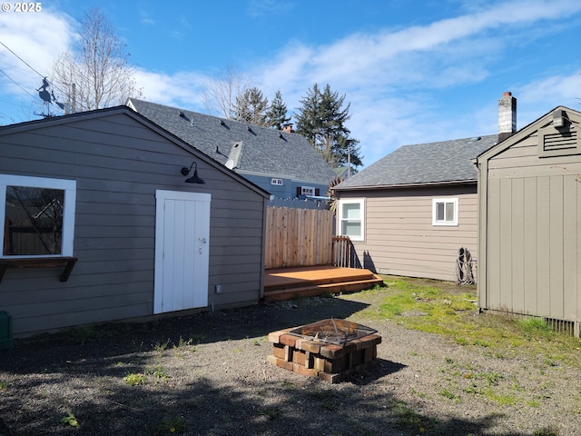 rear view of house with a storage unit, an outdoor structure, a fire pit, and a deck