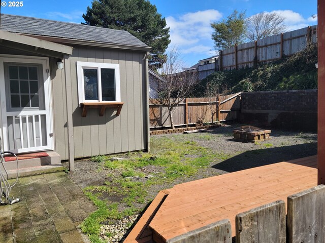 1063 Elrod Ave, Coos Bay, OR 97420 - view of yard with an outbuilding, a fire pit, a fenced backyard, and a wooden deck