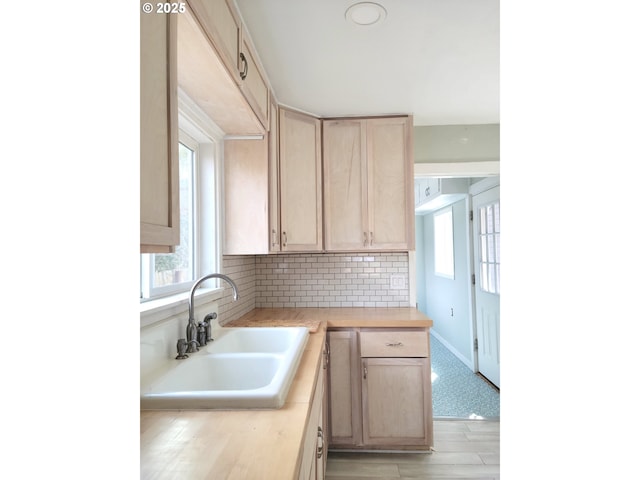 kitchen with a sink, light brown cabinets, a healthy amount of sunlight, and light countertops